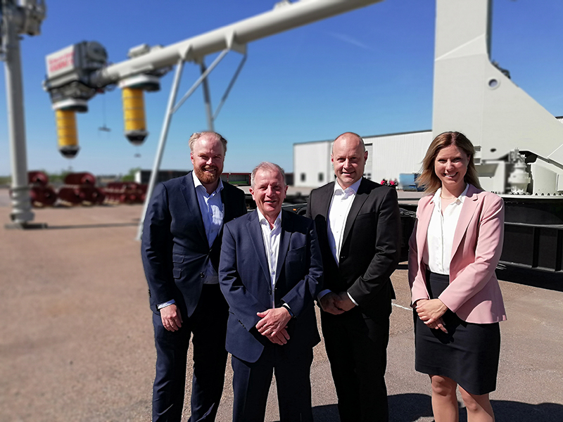 Three men and one woman posing in front of a mobile ship unloader