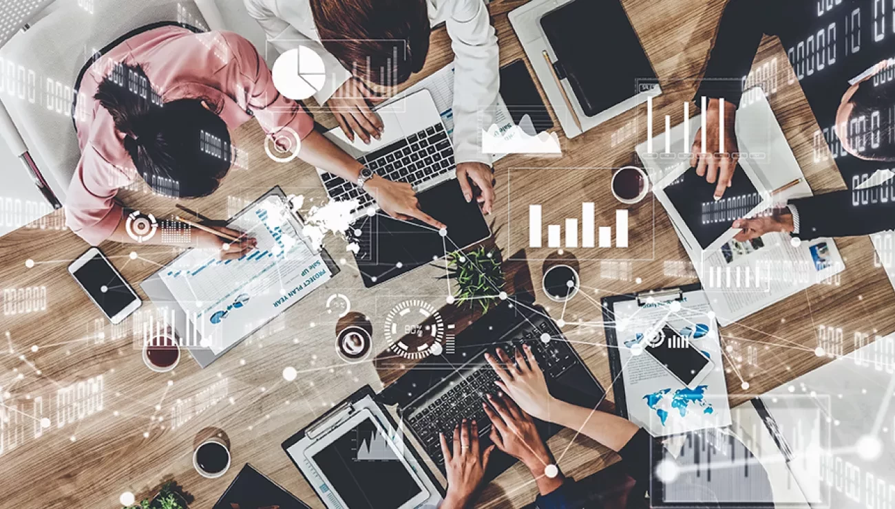 people sitting at table seen from above, working on computers