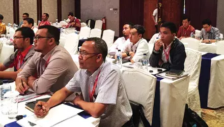 A group of people listening to a presenter in a conference room
