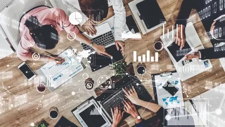people sitting at table seen from above, working on computers